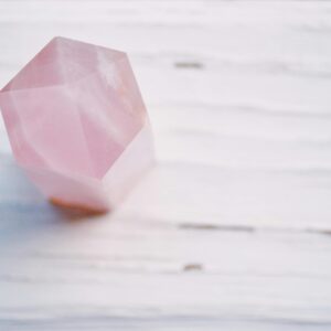 A pastel pink crystal with a soft focus on a textured surface, perfect for meditation themes.